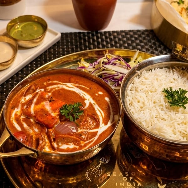 Indian meal with butter chicken, rice, naan, and various sauces on a golden tray.