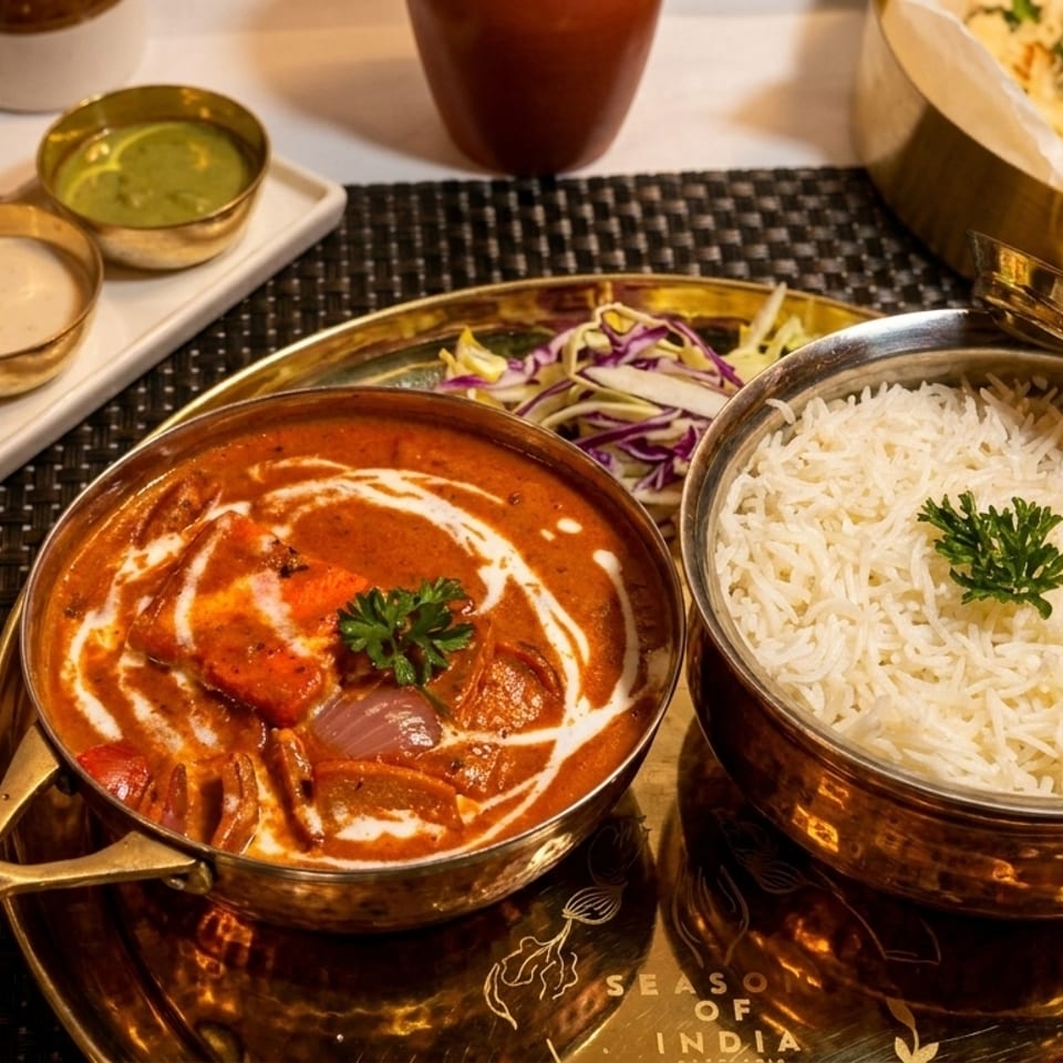 Indian meal with butter chicken, rice, naan, and various sauces on a golden tray.